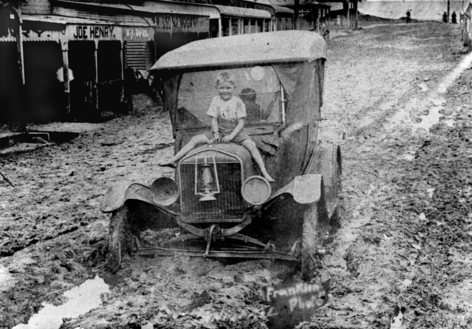 Date: Circa 1917-1927 Location: Rankin Street, Innisfail,  Who: Boy sitting on a car during the flood
